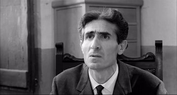 Movie still from “Seduced and Abandoned” (1964), directed by Pietro Germi – Black and white photograph of a man wearing a suit; Close Up shot, Low angle