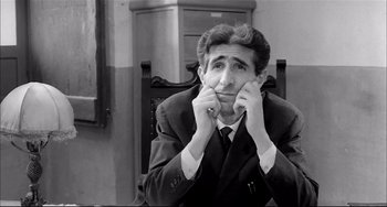 Movie still from “Seduced and Abandoned” (1964), directed by Pietro Germi – A black and white photo of a man sitting in a chair; Medium shot, High angle