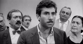 Movie still from “Seduced and Abandoned” (1964), directed by Pietro Germi – Black and white photograph of a man in a suit; Close Up shot, Low angle