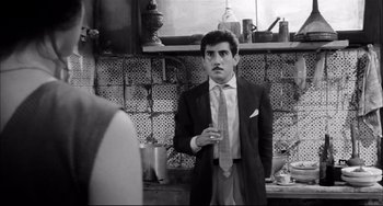 Movie still from “Seduced and Abandoned” (1964), directed by Pietro Germi – A black and white photo of a man in a suit and tie; Medium shot, Over the shoulder angle