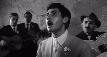 Movie still from “Seduced and Abandoned” (1964), directed by Pietro Germi – A black and white photo of a man singing; Close Up shot, Low angle