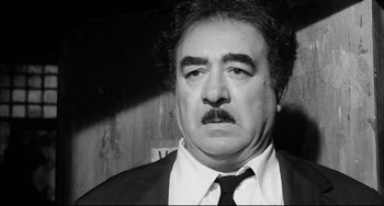 Movie still from “Seduced and Abandoned” (1964), directed by Pietro Germi – Black and white photograph of a man in a suit and tie; Close Up shot, High angle