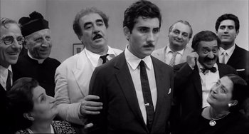 Movie still from “Seduced and Abandoned” (1964), directed by Pietro Germi – Black and white photograph of men in suits and ties; Medium shot, Over the shoulder angle