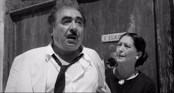 Movie still from “Seduced and Abandoned” (1964), directed by Pietro Germi – An older man and a woman standing next to each other; Medium shot, Low angle