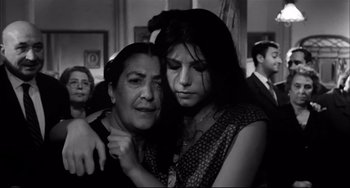 Movie still from “Seduced and Abandoned” (1964), directed by Pietro Germi – A woman and a woman hugging each other in front of a group of people; Close Up shot, Low angle