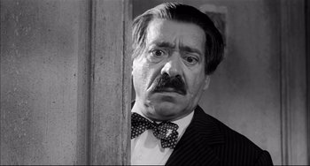 Movie still from “Seduced and Abandoned” (1964), directed by Pietro Germi – A man with a mustache and a bow tie; Close Up shot, Low angle