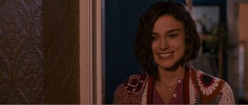 Movie still from “Seeking a Friend for the End of the World” (2012), directed by Lorene Scafaria – A woman smiling for the camera in front of a window; Close Up shot, Over the shoulder angle