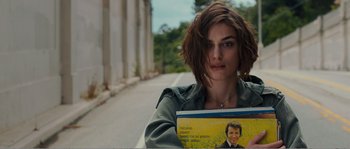Movie still from “Seeking a Friend for the End of the World” (2012), directed by Lorene Scafaria – A woman is holding a book while standing on the side of the road; Close Up shot, High angle
