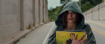 Movie still from “Seeking a Friend for the End of the World” (2012), directed by Lorene Scafaria – A woman in a hooded jacket holding a book; Close Up shot, Over the shoulder angle