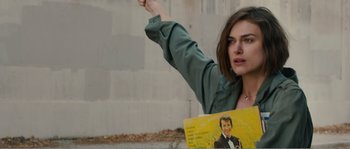 Movie still from “Seeking a Friend for the End of the World” (2012), directed by Lorene Scafaria – A woman holding up a picture of a man in a suit; Close Up shot, Low angle