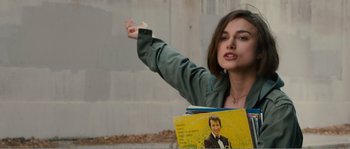 Movie still from “Seeking a Friend for the End of the World” (2012), directed by Lorene Scafaria – A woman is holding a book with a picture of a man; Medium shot, Over the shoulder angle