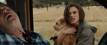 Movie still from “Seeking a Friend for the End of the World” (2012), directed by Lorene Scafaria – A woman holding a dog in her arms in a field; Close Up shot, Over the shoulder angle
