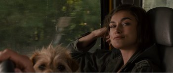 Movie still from “Seeking a Friend for the End of the World” (2012), directed by Lorene Scafaria – A woman sitting next to a dog on a bus; Close Up shot, Over the shoulder angle