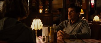 Movie still from “Seeking a Friend for the End of the World” (2012), directed by Lorene Scafaria – A man sitting at a table in front of a lamp; Medium shot, Over the shoulder angle