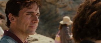 Movie still from “Seeking a Friend for the End of the World” (2012), directed by Lorene Scafaria – A person wearing a hat near rocks; Close Up shot, Over the shoulder angle