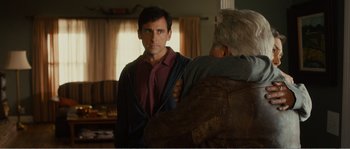 Movie still from “Seeking a Friend for the End of the World” (2012), directed by Lorene Scafaria – A man standing next to another man in front of a window; Medium shot, Over the shoulder angle