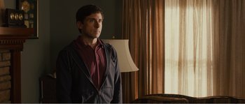 Movie still from “Seeking a Friend for the End of the World” (2012), directed by Lorene Scafaria – A man standing in front of a window in a room; Medium shot, Over the shoulder angle