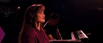 Movie still from “Selena” (1997), directed by Gregory Nava – A woman in a purple shirt is playing a piano; Close Up shot, Low angle
