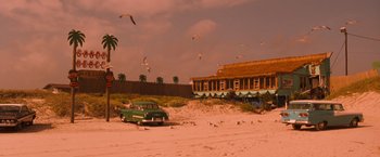 Movie still from “Selena” (1997), directed by Gregory Nava – An old car parked on the beach with seagulls flying overhead; Extreme Wide shot, Low angle