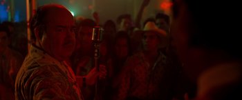 Movie still from “Selena” (1997), directed by Gregory Nava – A man holding a microphone in front of a group of people; Close Up shot, Low angle