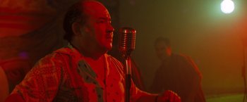 Movie still from “Selena” (1997), directed by Gregory Nava – An older man with a mustache is holding a microphone; Medium shot, Low angle