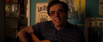 Movie still from “Selena” (1997), directed by Gregory Nava – A man in a striped shirt is holding a guitar; Close Up shot, Low angle