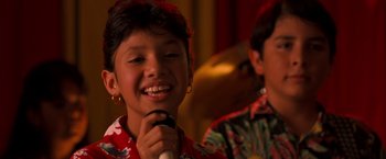 Movie still from “Selena” (1997), directed by Gregory Nava – A young girl smiles while holding a microphone; Close Up shot, High angle