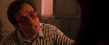 Movie still from “Selena” (1997), directed by Gregory Nava – An older man wearing glasses sitting in front of a window; Close Up shot, Low angle