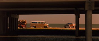 Movie still from “Selena” (1997), directed by Gregory Nava – A van driving down a street under a bridge; Wide shot, Low angle