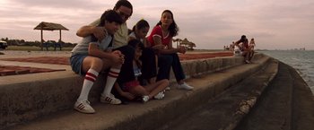 Movie still from “Selena” (1997), directed by Gregory Nava – A group of people sitting on the side of a road; Wide shot, High angle