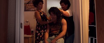 Movie still from “Selena” (1997), directed by Gregory Nava – A man getting his hair combed by two women; Medium shot, High angle