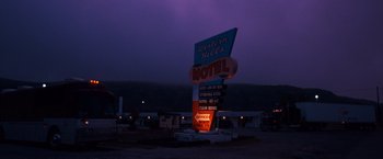 Movie still from “Selena” (1997), directed by Gregory Nava – A motel sign lit up at night in the dark; Extreme Wide shot, Low angle
