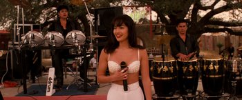 Movie still from “Selena” (1997), directed by Gregory Nava – A woman holding a microphone in her hand; Medium shot, Over the shoulder angle