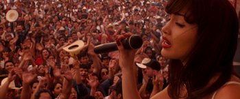 Movie still from “Selena” (1997), directed by Gregory Nava – A woman singing into a microphone in front of a crowd; Medium shot, High angle