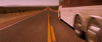 Movie still from “Selena” (1997), directed by Gregory Nava – A bus driving down the middle of a road; Extreme Wide shot, High angle
