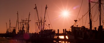 Movie still from “Selena” (1997), directed by Gregory Nava – The sun is setting over the water with a boat in the background; Extreme Wide shot, Low angle