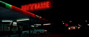 Movie still from “Selena” (1997), directed by Gregory Nava – A car parked in front of a lit up sign; Wide shot, Low angle