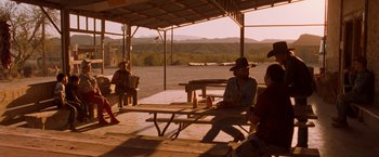 Movie still from “Selena” (1997), directed by Gregory Nava – A group of people sitting at picnic tables under a shelter; Wide shot, Over the shoulder angle