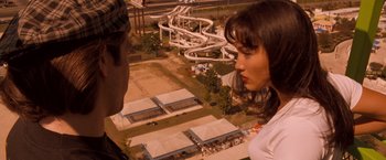 Movie still from “Selena” (1997), directed by Gregory Nava – A man and a woman standing next to each other in front of a roller coaster; Close Up shot, High angle