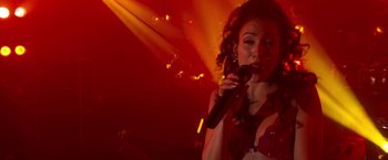 Movie still from “Selena” (1997), directed by Gregory Nava – A woman holding a microphone in her hand; Close Up shot, High angle