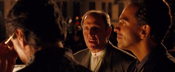 Movie still from “Selena” (1997), directed by Gregory Nava – A man in a suit is talking to two other men; Close Up shot, Over the shoulder angle