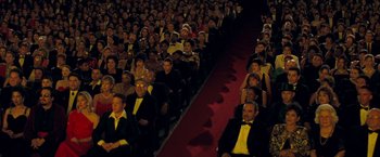 Movie still from “Selena” (1997), directed by Gregory Nava – A group of people sitting in rows in front of a red carpet; Extreme Wide shot, High angle
