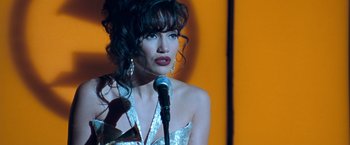 Movie still from “Selena” (1997), directed by Gregory Nava – A woman in a white dress is speaking on a microphone; Close Up shot, Over the shoulder angle