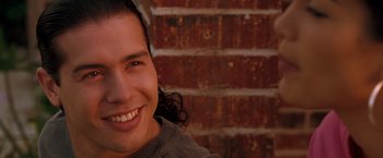 Movie still from “Selena” (1997), directed by Gregory Nava – A man with long black hair smiling for the camera; Close Up shot, Low angle