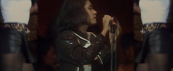 Movie still from “Selena” (1997), directed by Gregory Nava – A woman holding a microphone in her hand; Close Up shot, High angle