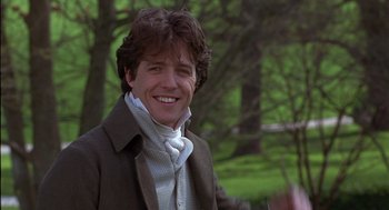 Movie still from “Sense and Sensibility” (1995), directed by Ang Lee – A man smiling for the camera in a wooded area; Close Up shot, Over the shoulder angle