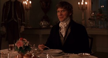 Movie still from “Sense and Sensibility” (1995), directed by Ang Lee – A man sitting at a dinner table with a plate in front of him; Medium shot, Over the shoulder angle