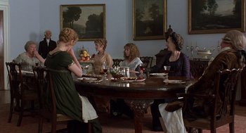 Movie still from “Sense and Sensibility” (1995), directed by Ang Lee – A group of people sitting around a table with plates of food on top of it; Wide shot, High angle