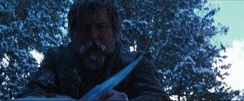 Movie still from “Seraphim Falls” (2006), directed by David Von Ancken – A man with a beard holding a knife in the snow; Close Up shot, Low angle