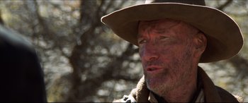 Movie still from “Seraphim Falls” (2006), directed by David Von Ancken – An older man wearing a brown hat and a brown jacket; Close Up shot, Over the shoulder angle